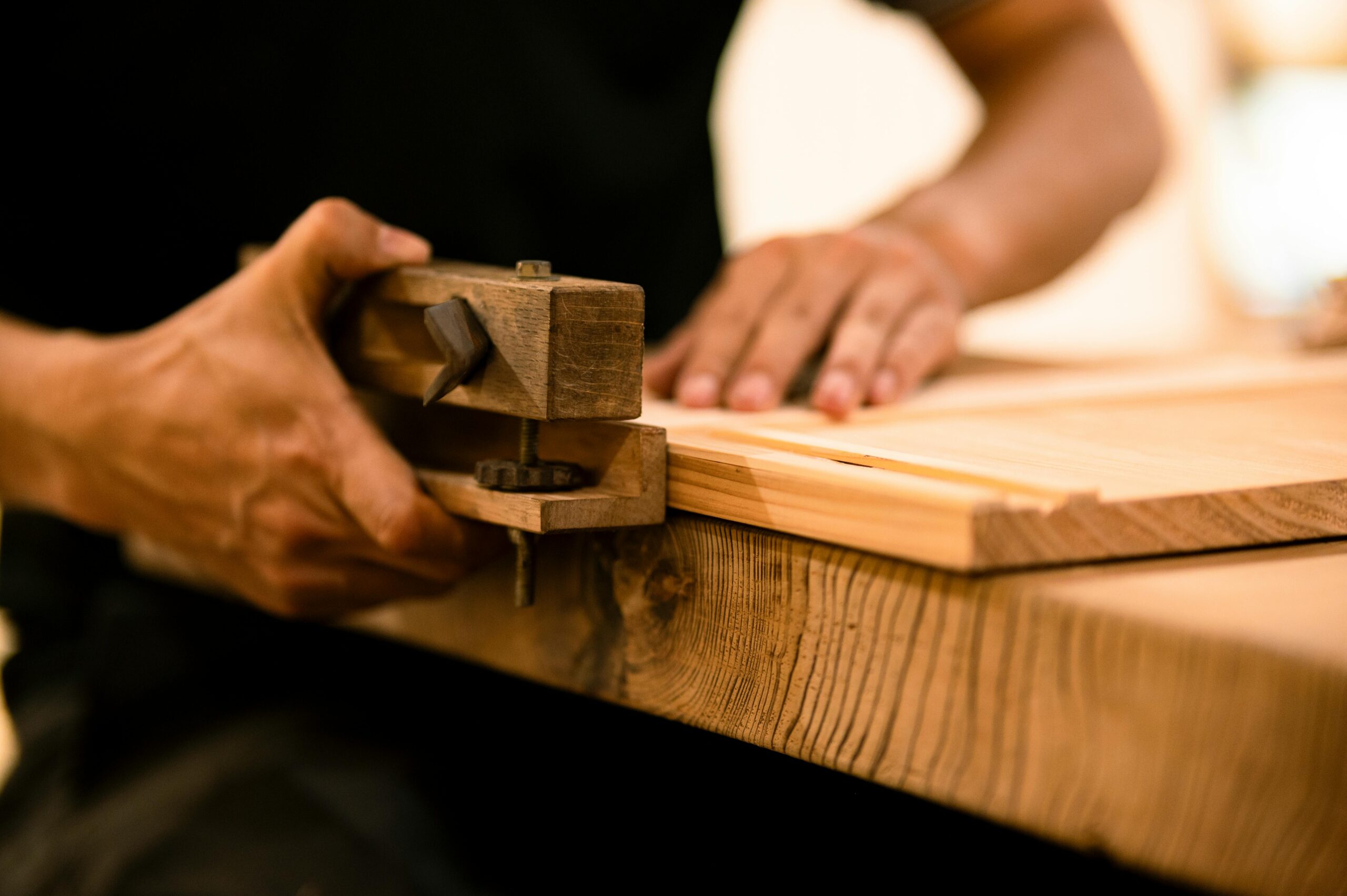 Home A skilled woodworker shaping wood with a hand tool in a workshop, showcasing craftsmanship and precision.