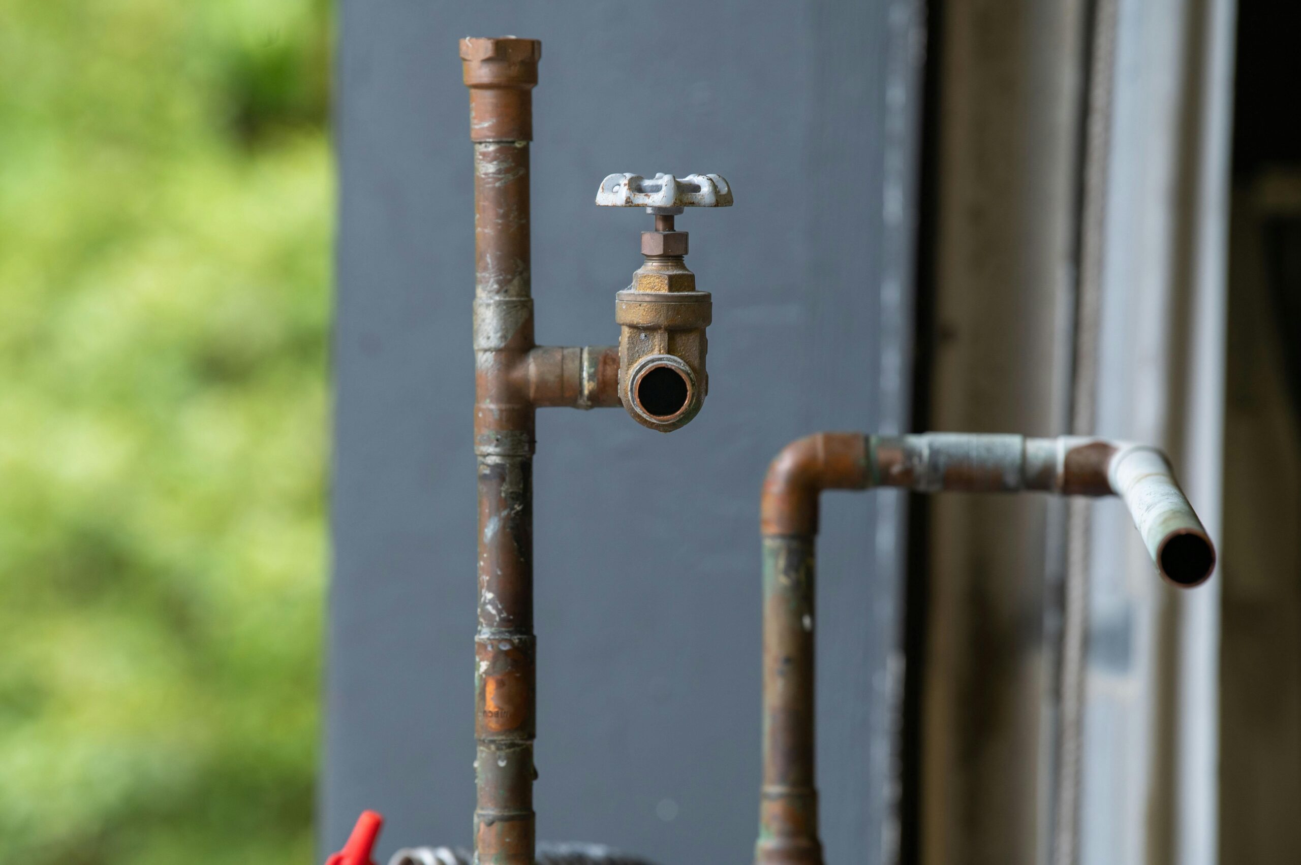 Home Detailed view of an old, rusty industrial water pipe with valve, conveying vintage industrial aesthetics.